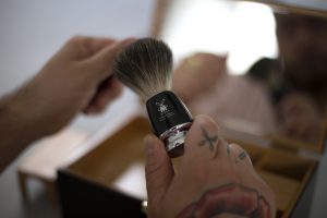 Een Mühle scheerkwast van dassenhaar vastgehouden door een mannenhand met tatoeages